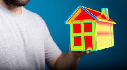 A person holds a model house representing energy efficiency and smart home concepts. Illustrating...
