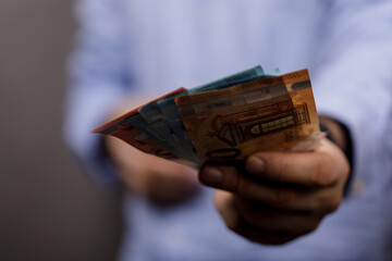 Close-up shot of a man's hand holding Euro banknotes, illustrating financial concepts like wealth,...