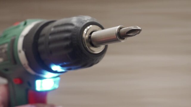 The metal and plastic electric screwdriver is operating slowly. The bit is rotating, creating a soft, continuous whirring sound.