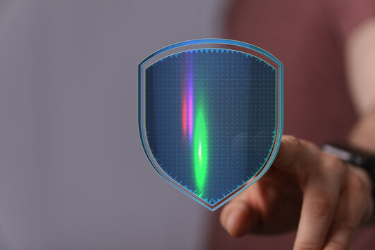 Hand touching a glowing shield icon representing data protection, cybersecurity, and secure technology. Symbolizes safeguarding digit