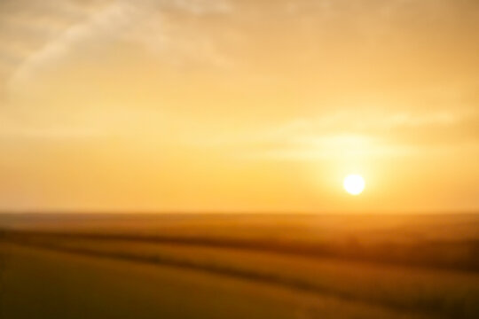 a sunrise or sunset over a field. blurred abstract background or banner with copy space. beauty glowing gradient of orange and yellow. cloudscape design element