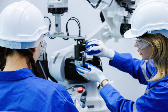 female automation machine engineer student study and inspection control robot arm machine in university or factory workshop. ai robot technology new innovation trend of manufacturing in industry 5.0