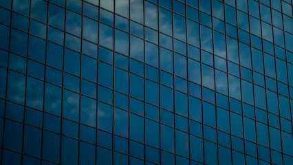 Modern glass skyscraper facade background reflecting blue sky and clouds. Abstract contemporary urban architecture. Business or real estate banner with copy space.
