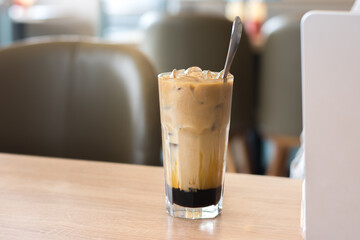 Iced palm sugar coffee on table while woman works on laptop at cafe