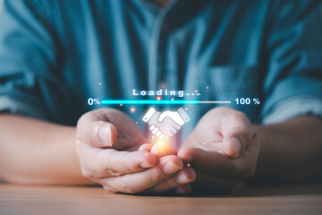 Close-up of hands holding a digital handshake icon with loading progress bar representing online...