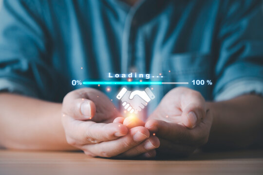 Close-up of hands holding a digital handshake icon with loading progress bar representing online business partnership trust technology connection and successful collaboration concept.
