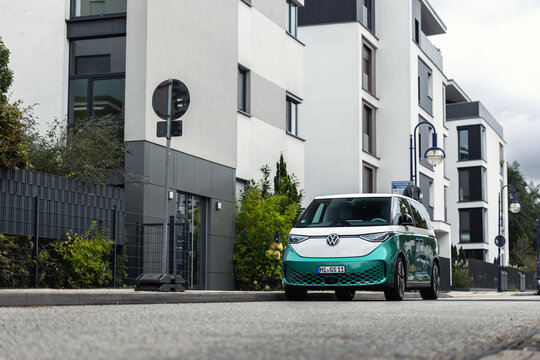 Magdeburg, Germany - October 3rd, 2024. Modern electric VW ID Buzz van parked residential street contemporary buildings background. Future urban sustainability lifestyle