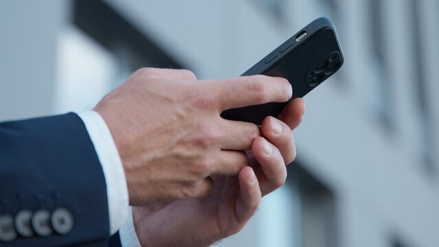 Close-up male hands holding mobile phone in city unrecognizable business man chatting with smartphone device unknown businessman with cellphone sending sms message using online cyberspace internet