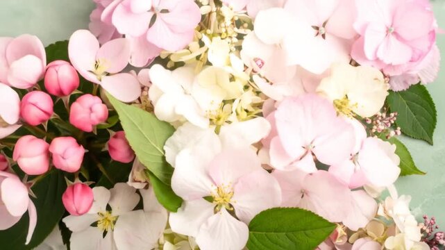 Close-up of varied pastel-colored flowers, against a textured seafoam green background