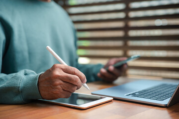 Businessman multitasking using digital pen on tablet, smartphone, and laptop, representing productivity, digital workflow, modern communication, and technology integration in contemporary workspace.