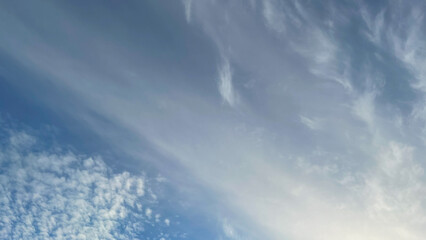 Blue sky with a gradient of light and soft, streaky white clouds. Serene and peaceful atmosphere