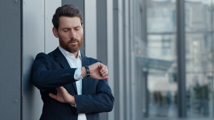 Caucasian mature business man looking at wristwatch in city smiling businessman adult male employer waiting for meeting happy manager entrepreneur checking time wait standing near office building