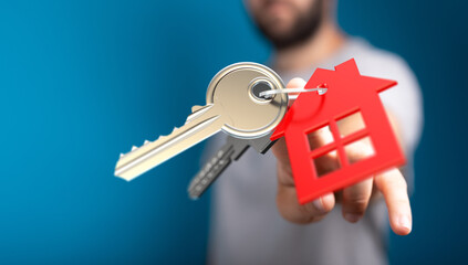 Person showing key with house shape. Concept of real estate, mortgage, home ownership, buying or renting property, new beginnings and security.