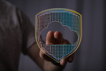Secure cloud data storage and privacy concept. A hand holding a glowing digital shield with a cloud...