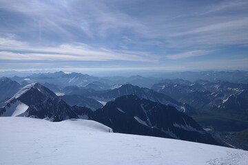 Tranquil Lake With Lush Green Forest, Snow-Capped Mountain, Blue Sky And White Clouds