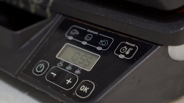 The electric grill is cooking chicken. When the timer finishes, the device emits a loud beep sound.