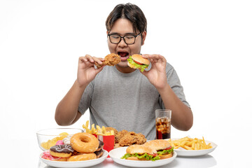 Young Asian fat man enjoy to eating unhealthy junk food, hamburger and fried chicken, studio shot.
