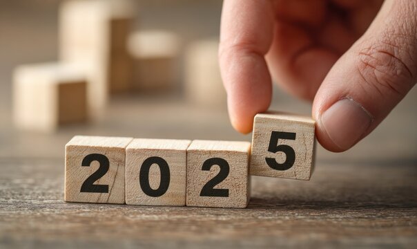Hand placing wooden block to form the year 2025.