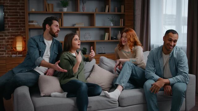 Multiracial four friends at home party talking on couch emotional discussion arguing smiling diverse people communicate in living room women girls men guys together conversation debate problem discuss