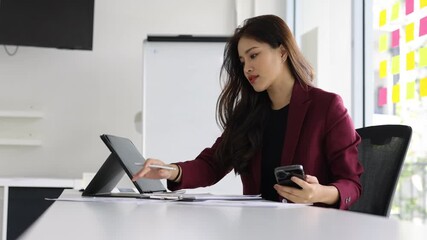 Young businesswoman analyzing data and using smartphone in the office. - Powered by Adobe