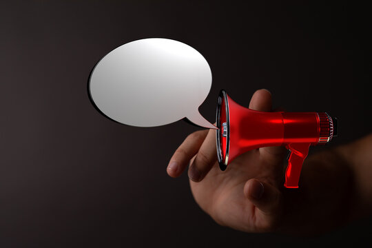 A hand holds a red megaphone with a speech bubble, perfect for concepts like announcement, communication, or marketing.