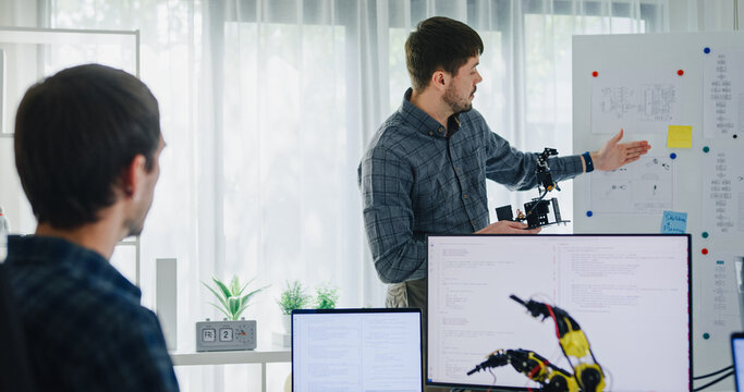 Team adult male engineer develop present AI robotics hand project at tech workspace. Artificial intelligence, collaboration support prototype development, robotic, debugging, machine learn, training.