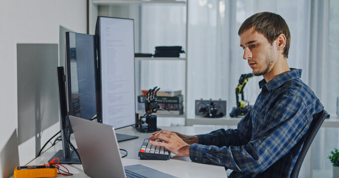 Young adult male freelance developer typing write prompt AI bot app program nomad terminal with coding at office. Artificial intelligence dashboard, robotics, user interface, machine learning concept.