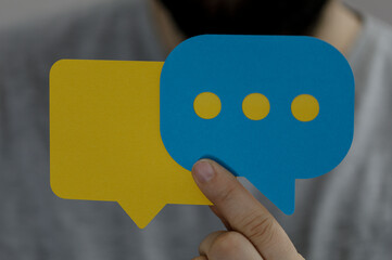 Person holding up two colorful chat bubbles representing dialog, conversation and communication. Idea, brainstorming, connection and teamwork.