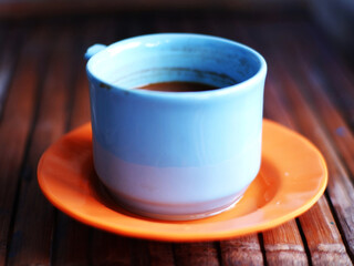 a cup of Coffee in Blue Mug – Rustic Orange Saucer on Wood