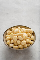A bowl filled with raw gnocchi placed against a light background.