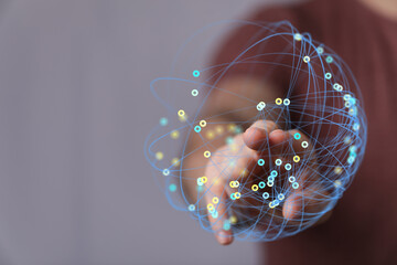 Abstract image of a person's hand holding a globe of interconnected nodes. Symbolizes...