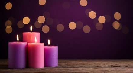 Four lit candles in purple and pink hues stand on a wooden surface against a blurred purple background with bokeh lights