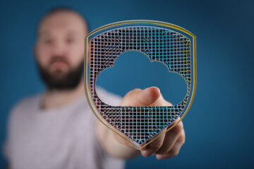 A man's hand holding a shield with a cloud shape, symbolizing data security and cloud computing on...