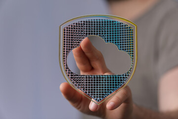 Hand holding a digital shield with cloud shape, representing data security, network protection, and...
