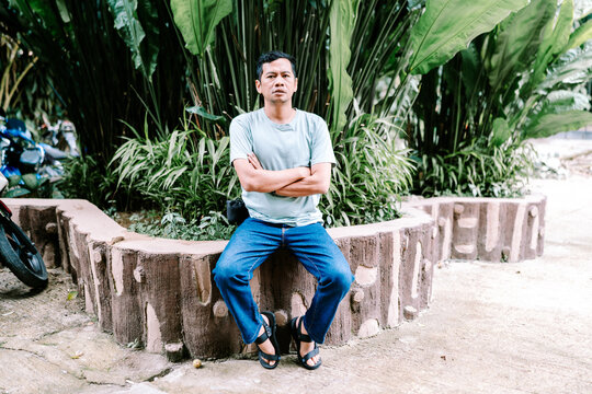 Casual Young Man Sits Relaxed Amidst Tropical Greenery