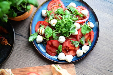 Top view of a fresh Caprese salad with baby mozzarella, ripe tomatoes, and herbs. The colorful and vibrant presentation highlights the freshness of the ingredients and the simplicity 