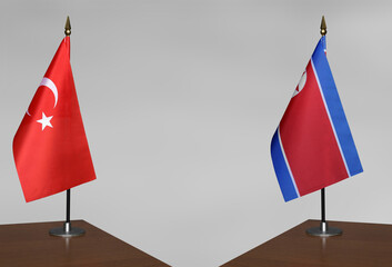 Table flags of Turkey and North Korea on grey blurred background