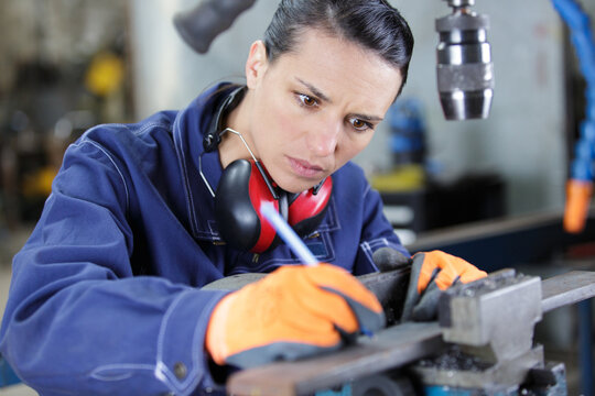 woman marking metal in a vice