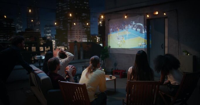 Friends Gather on a Rooftop, Watching Live Basketball Match on a Projector. They Enjoy Sports Entertainment, Cheering and Celebrating Teams Championsip Victory. City View Terrace World Tournament Cup