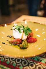 Exquisite Mediterranean appetizer: creamy burrata cheese atop vibrant tomato slices, garnished with fresh cilantro and drizzled with balsamic glaze. Served on a warm-toned plate — a feast for the eyes