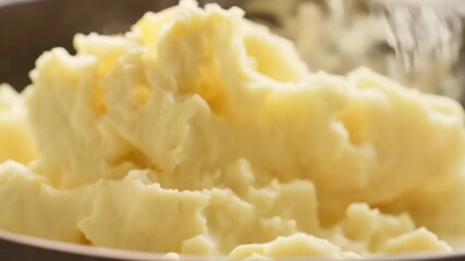 Smooth mashed potatoes are gently stirred with spoon in warm kitchen environment, releasing visible steam and soft creamy texture under natural light - Powered by Adobe