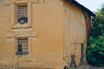 ひび割れて崩れかけた土壁の蔵と鉄格子の窓 日本の歴史的建築
