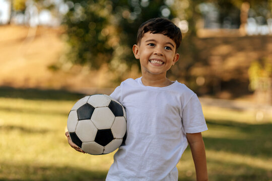 Happy boy holding soccer ball outdoors on a sunny day