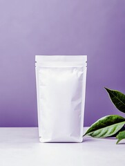 A blank white resealable pouch bag stands on a light surface next to green leaves, with a soft purple background.