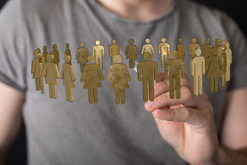 An image of a hand holding a group of gold human figures, representing teamwork, unity, and...
