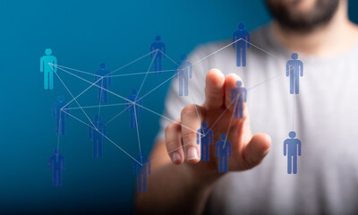 Hand reaching towards a network of connected human icons symbolizing social networking, teamwork, and collaboration.