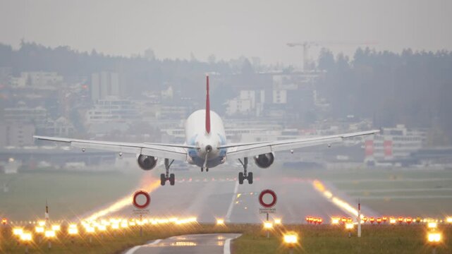 Rear long shot footage of a commercial passenger plane moments before touchdown. Real time, super telephoto footage, foggy autumn weather, illuminated runway, international flight, European Airport 