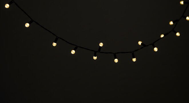 A string of warm yellow fairy lights glowing softly against a dark, minimalist background, creating a cozy ambiance