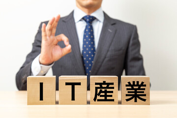 Obraz premium 「IT産業」と書かれたブロックとOKポーズをするビジネスマン
