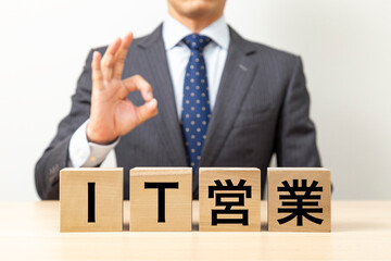 Obraz premium 「IT営業」と書かれたブロックとOKポーズをするビジネスマン